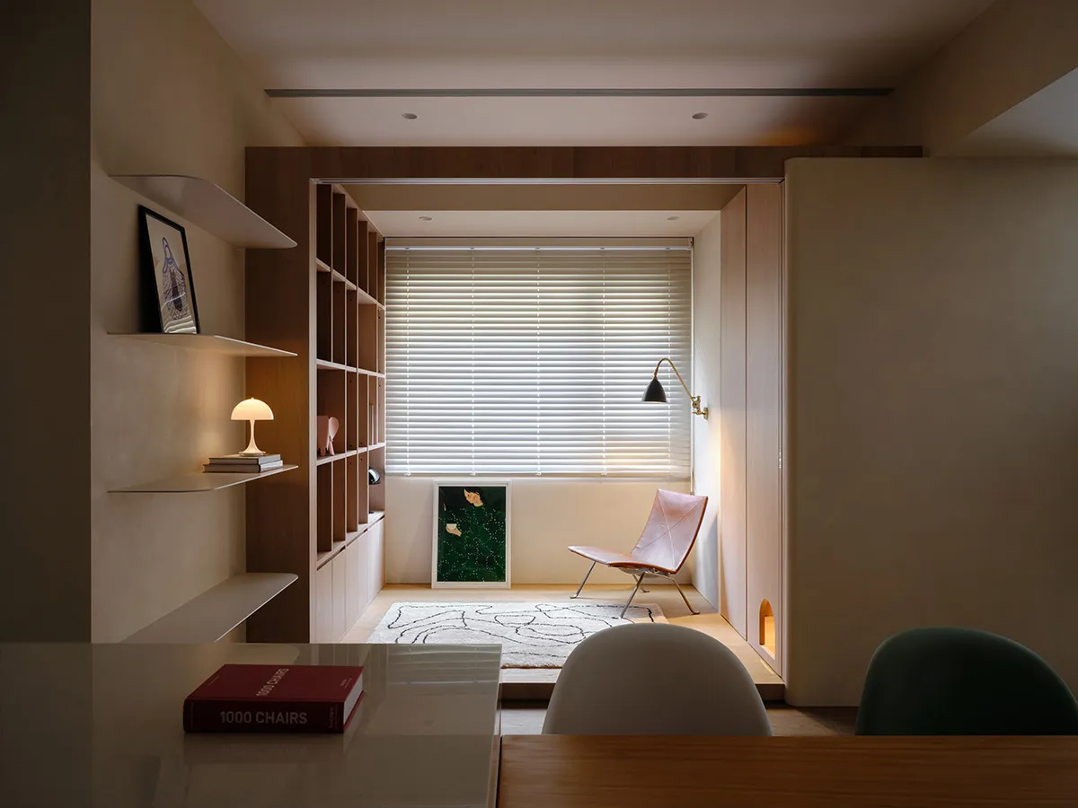 A minimalist residential interior with a sleek, contemporary design featuring wooden finishes and a window with blinds.
