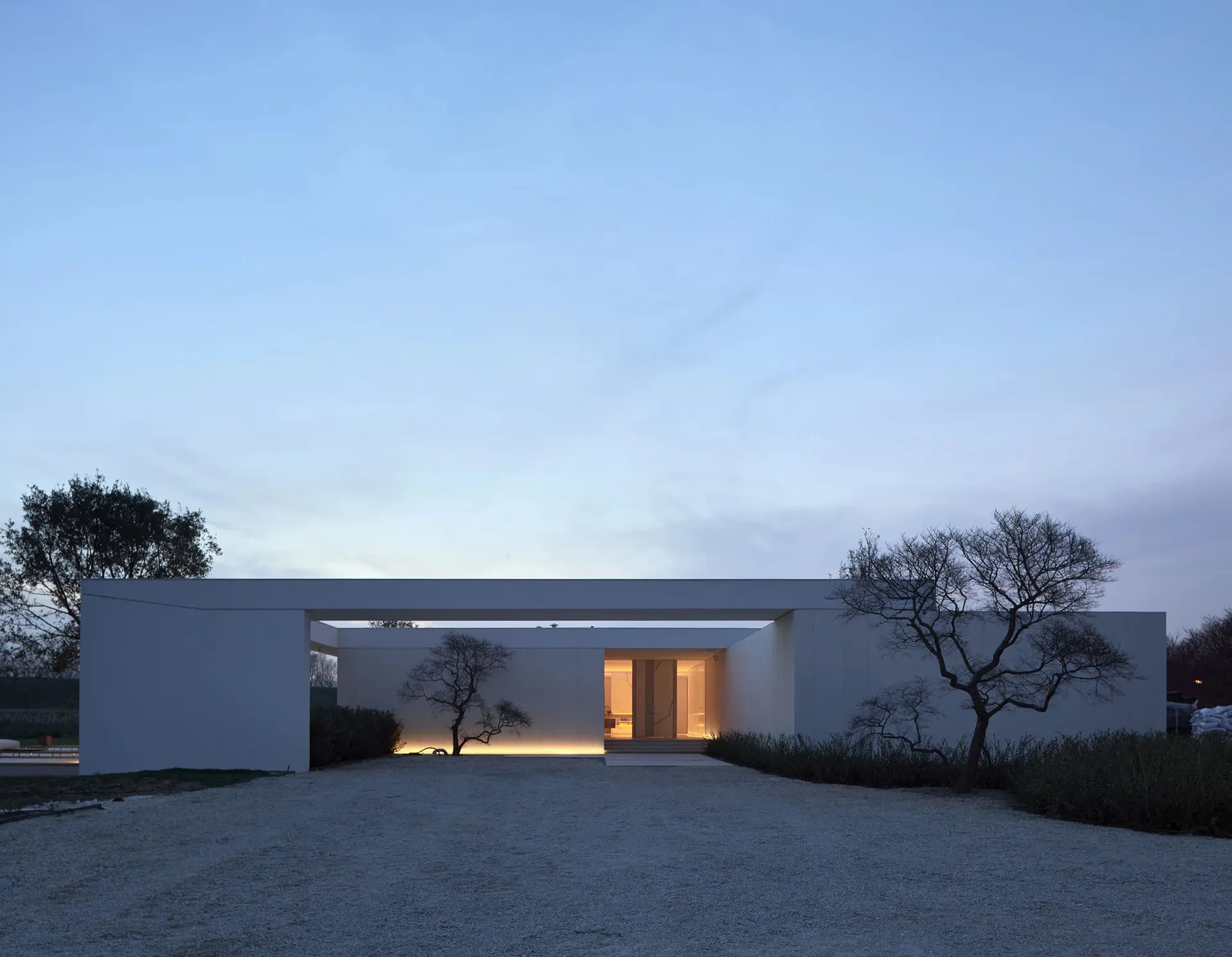 A minimalist concrete house with a modern design on a hillside.