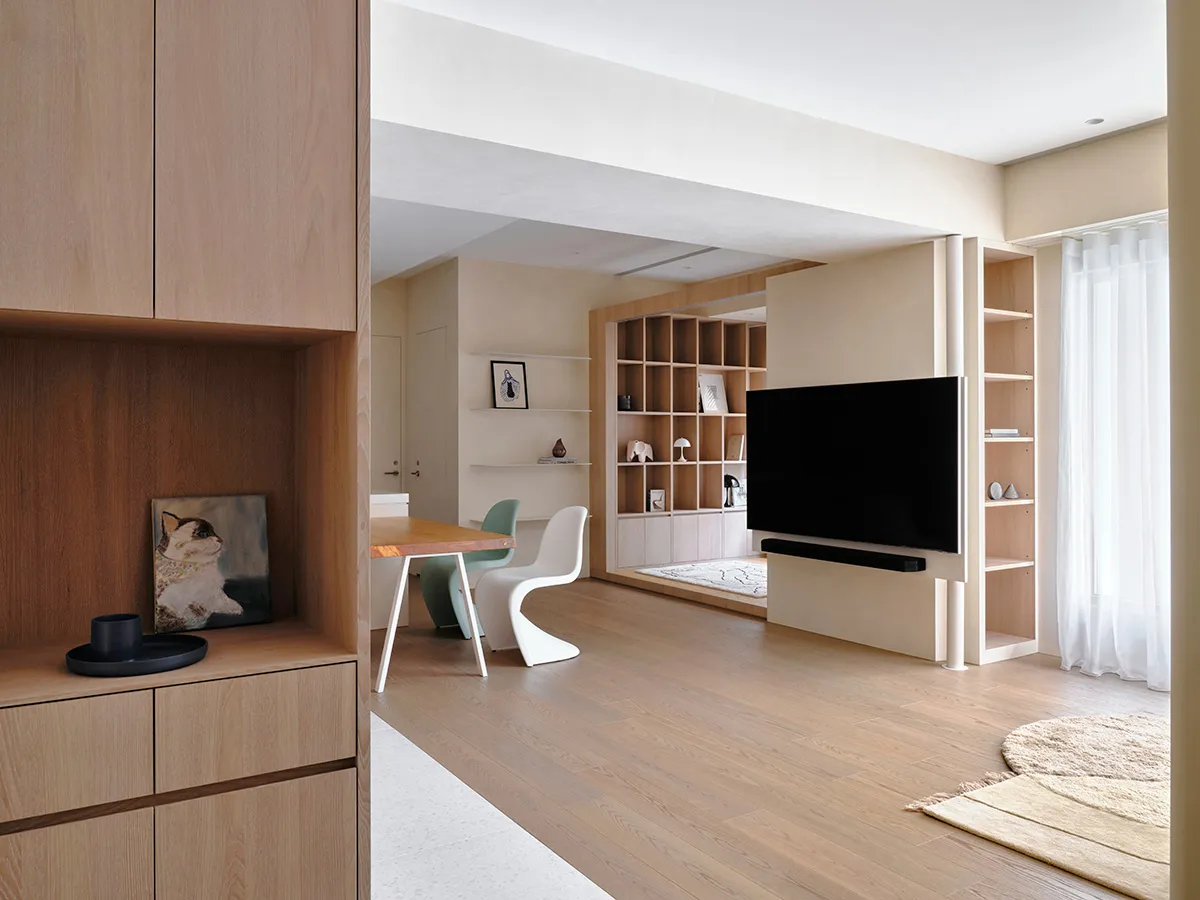 A minimalist living room featuring wooden furniture and textile accents.