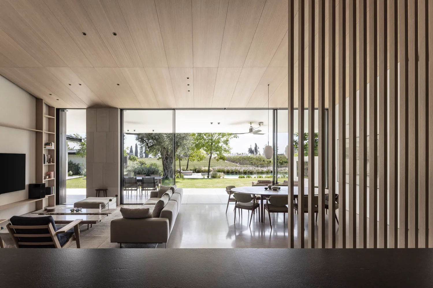 Modern residential space featuring wooden and concrete materials with open layout and large windows.