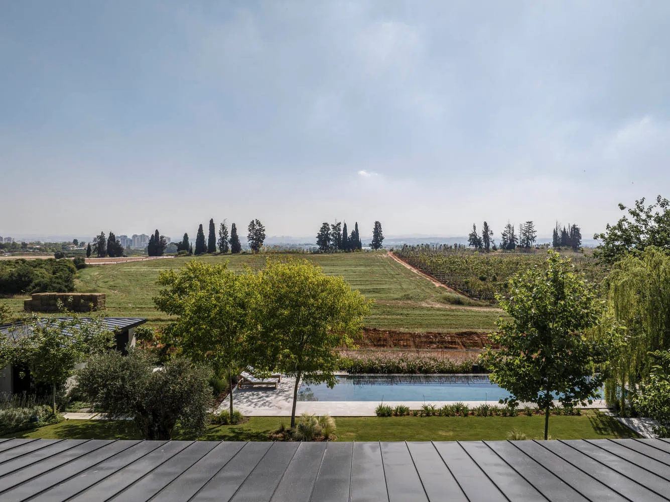 A serene pool surrounded by greenery with a beautiful view of the countryside and cityscape in the distance.