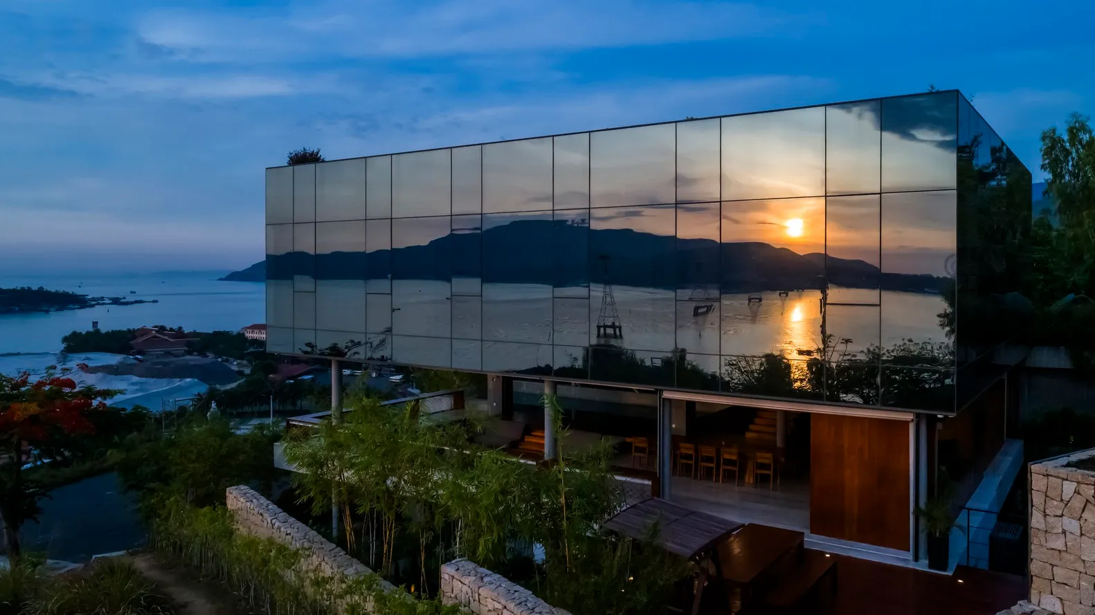 Modern residential hotel with glass exterior reflecting sunset.
