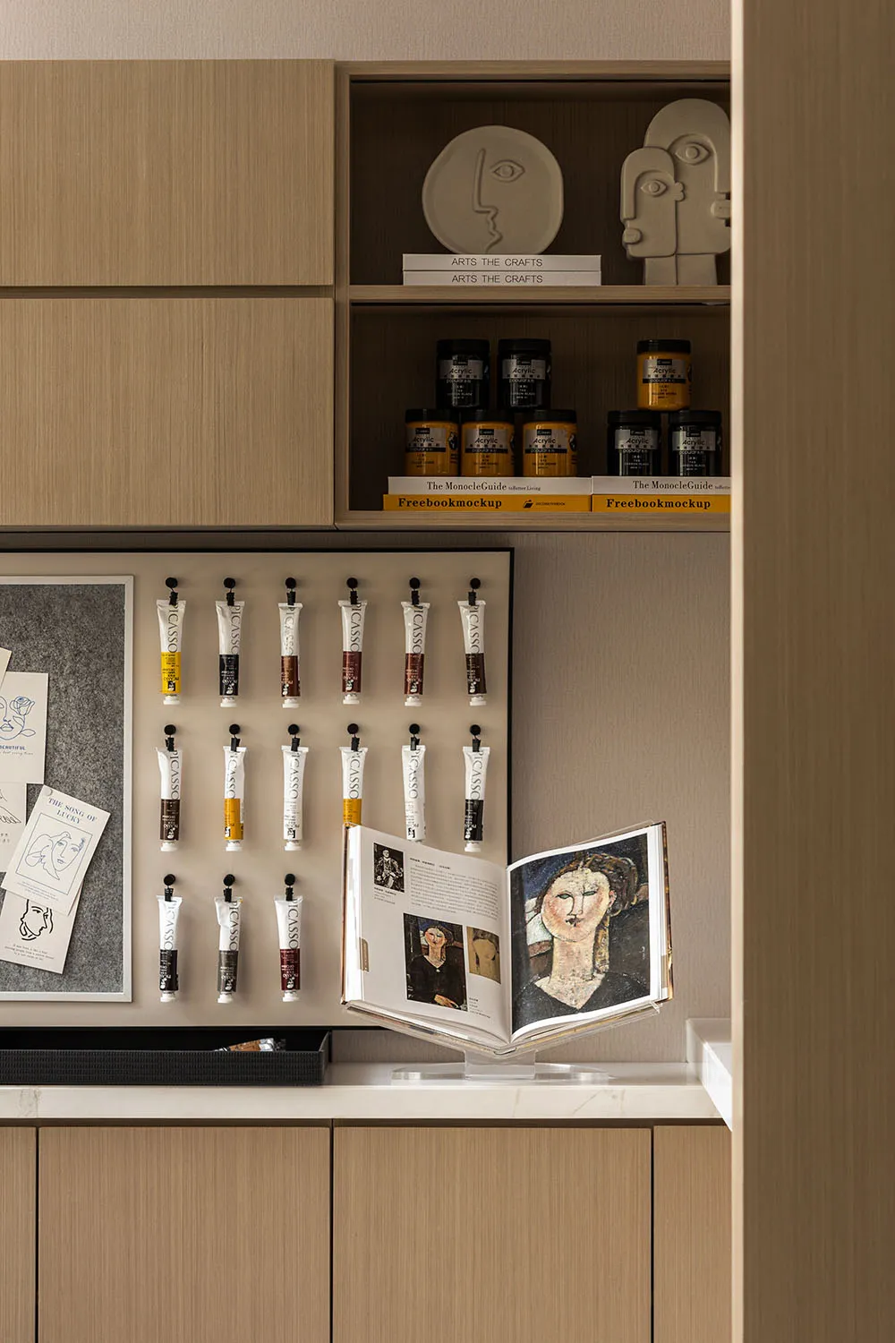 Art supply storage unit featuring minimalist design with wood material and various acrylic paints arranged neatly on shelves.
