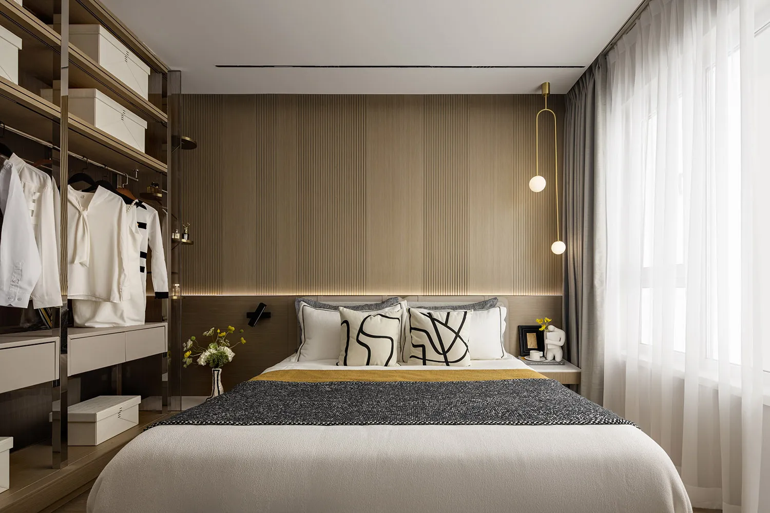 Modern bedroom featuring minimalist design with neutral-toned wood materials and a comfortable bed surrounded by a cozy readi