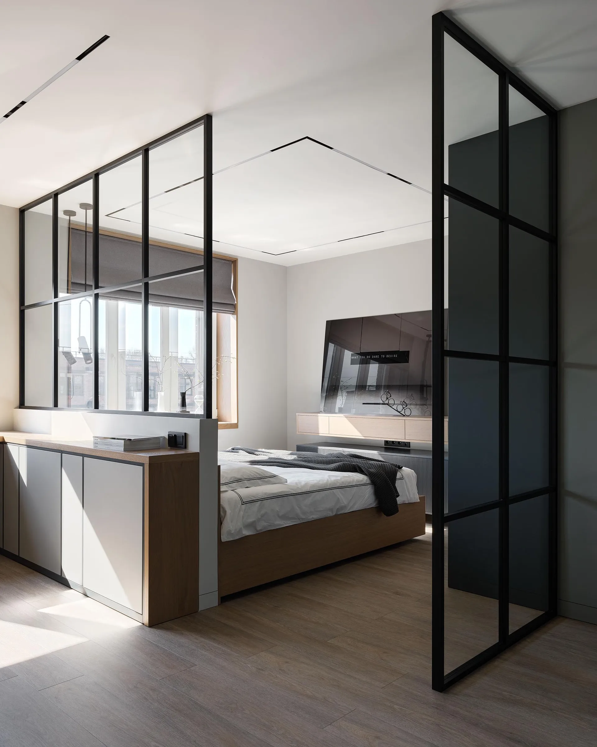 Modern bedroom with a glass and metal wall, wooden flooring, and a bed with white bedding.