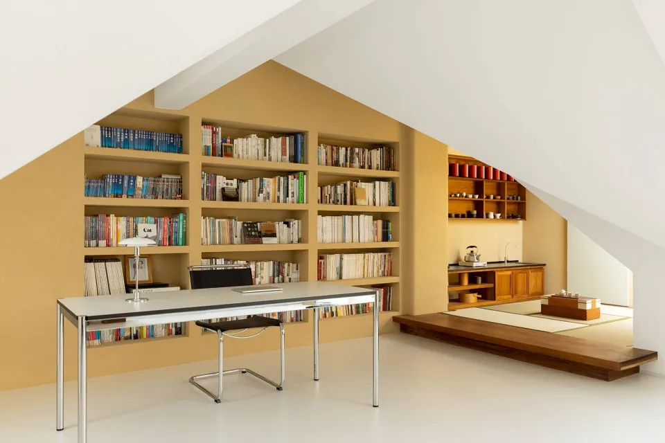 A modern home office with built-in bookshelves filled with books and a minimalist desk and chair.