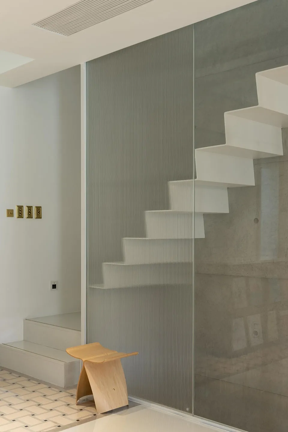 Modern interior design featuring a minimalist white staircase enclosed with frosted glass walls.