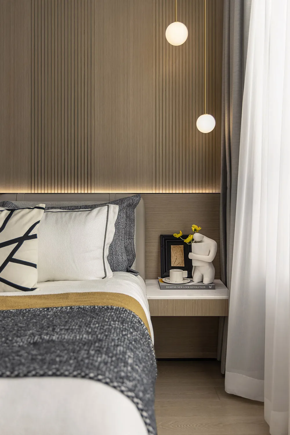Modern minimalist bedroom with wooden texture, featuring a bed with white and gray pillows and a white nightstand with a scul