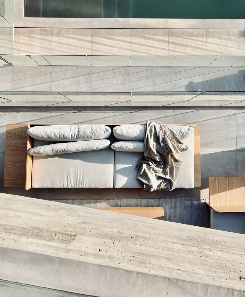 Modern outdoor sectional sofa with concrete frame and white cushions.