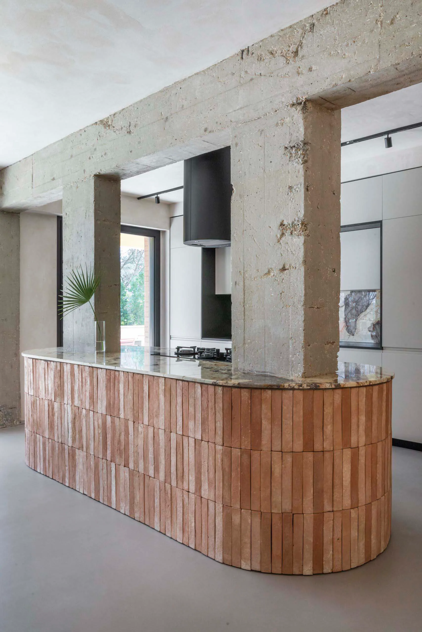 Modern minimalist kitchen featuring a wooden island with concrete columns and countertops.