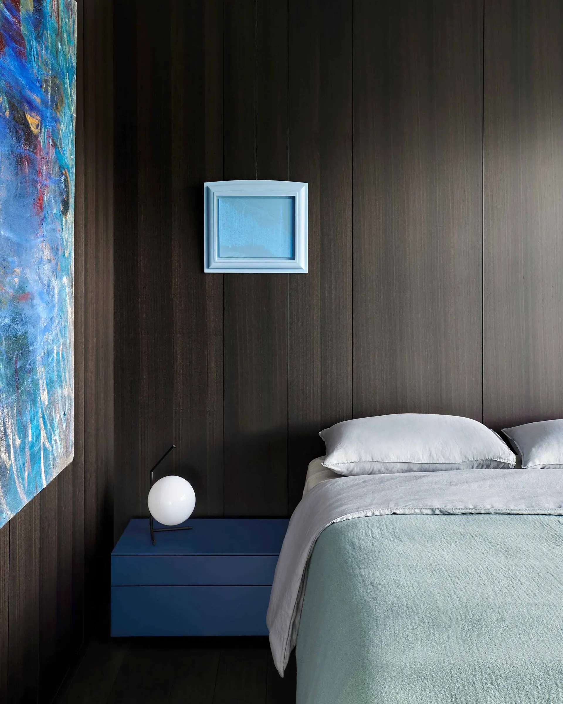 Modern bedroom featuring metallic headboard and bedside lamp.