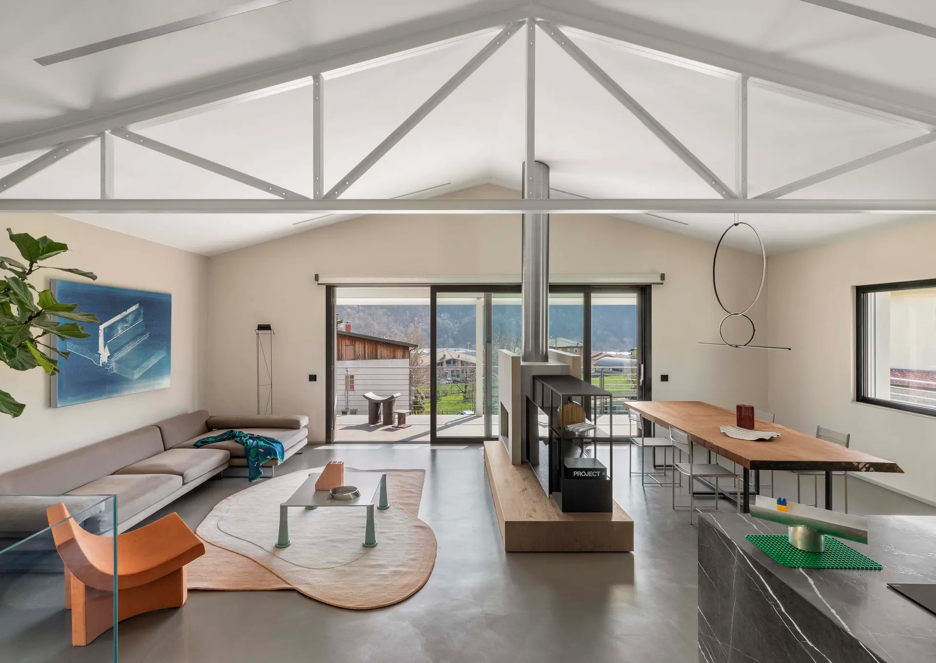 Modern industrial living room with concrete walls and floor, featuring minimalist furniture and large windows.