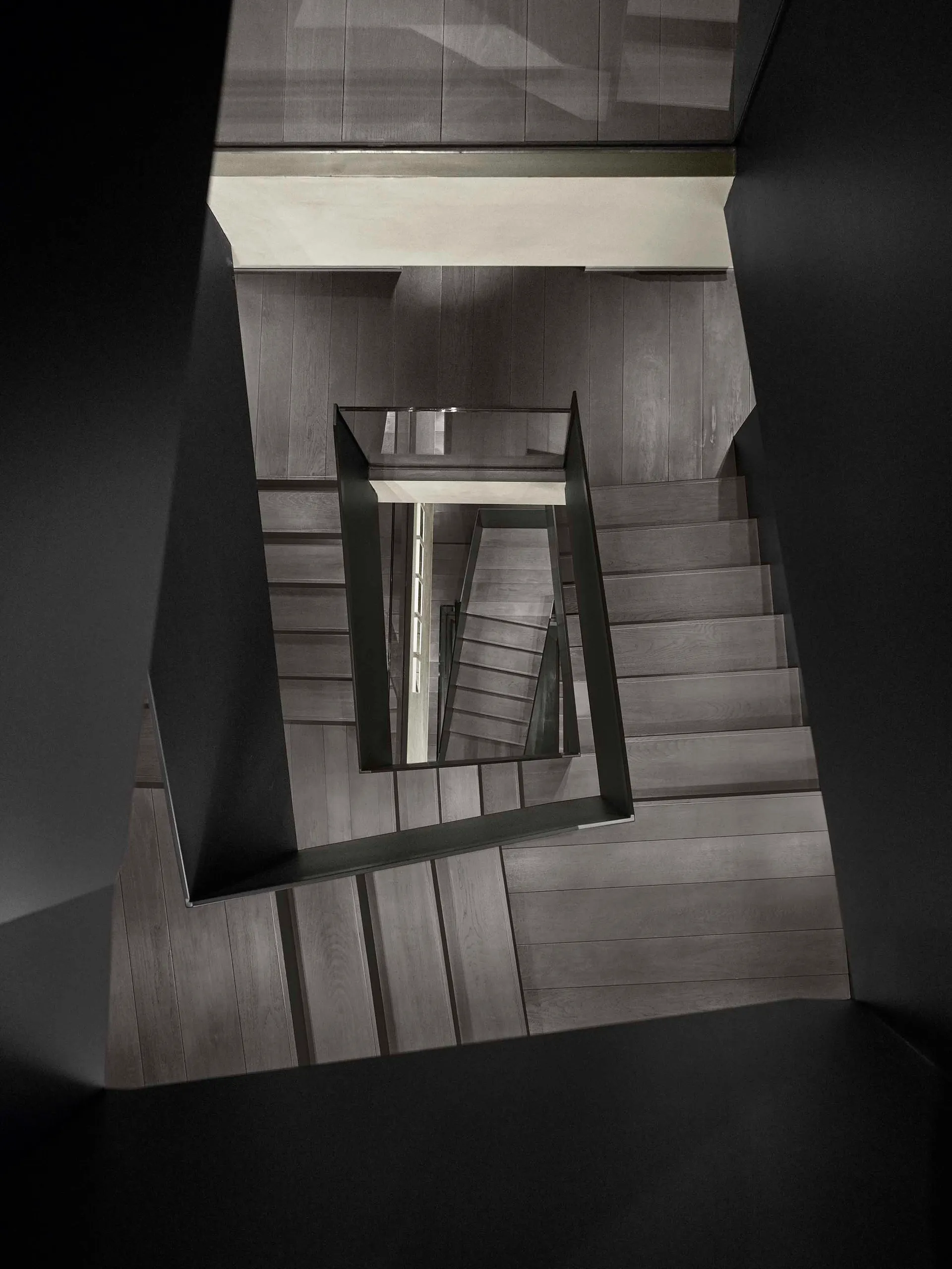 A modern interior featuring a wooden staircase with glass railings.