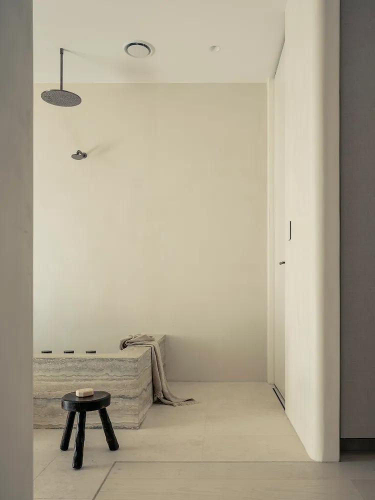 Minimalist bathroom with concrete walls, floor, and a simple shower setup.