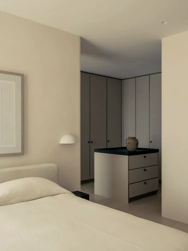 Minimalist bedroom with neutral-colored cabinets and a bed.