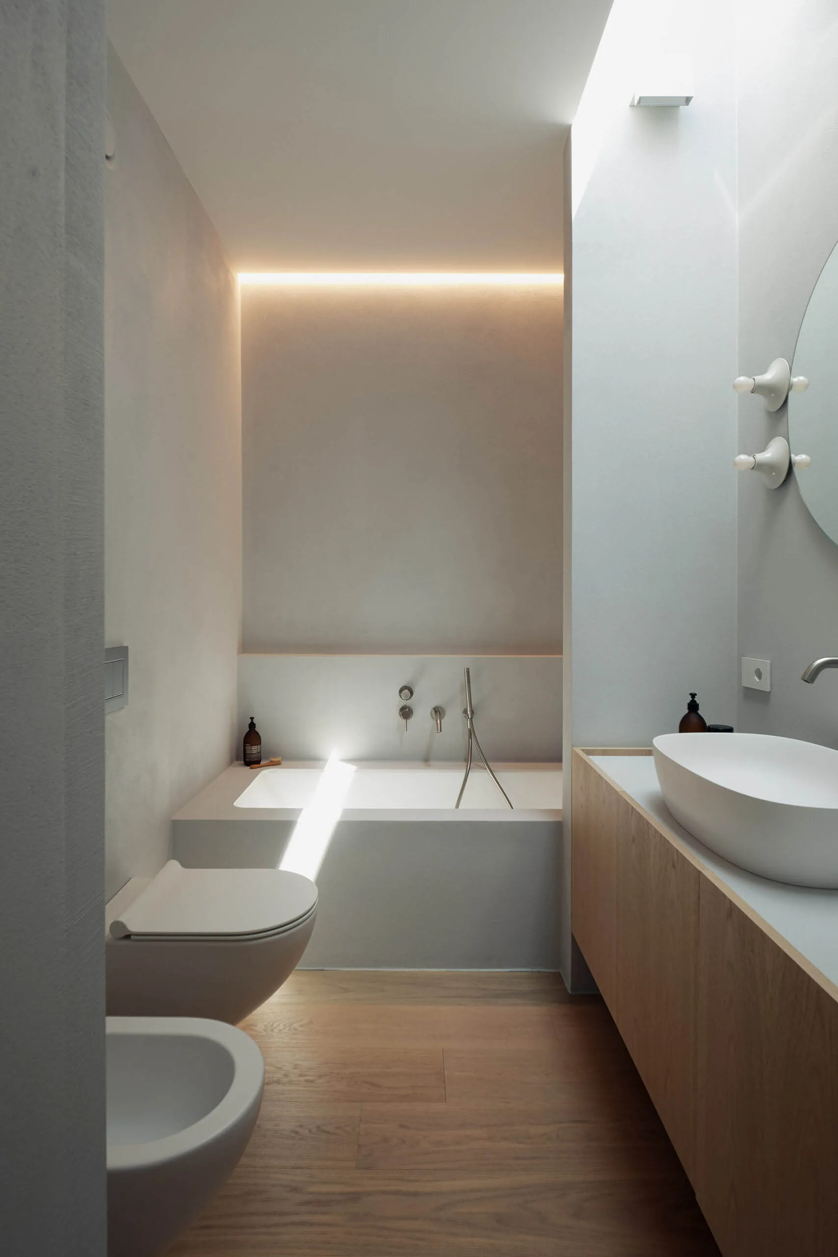 Minimalist bathroom featuring a concrete bathtub and sink with a wooden vanity