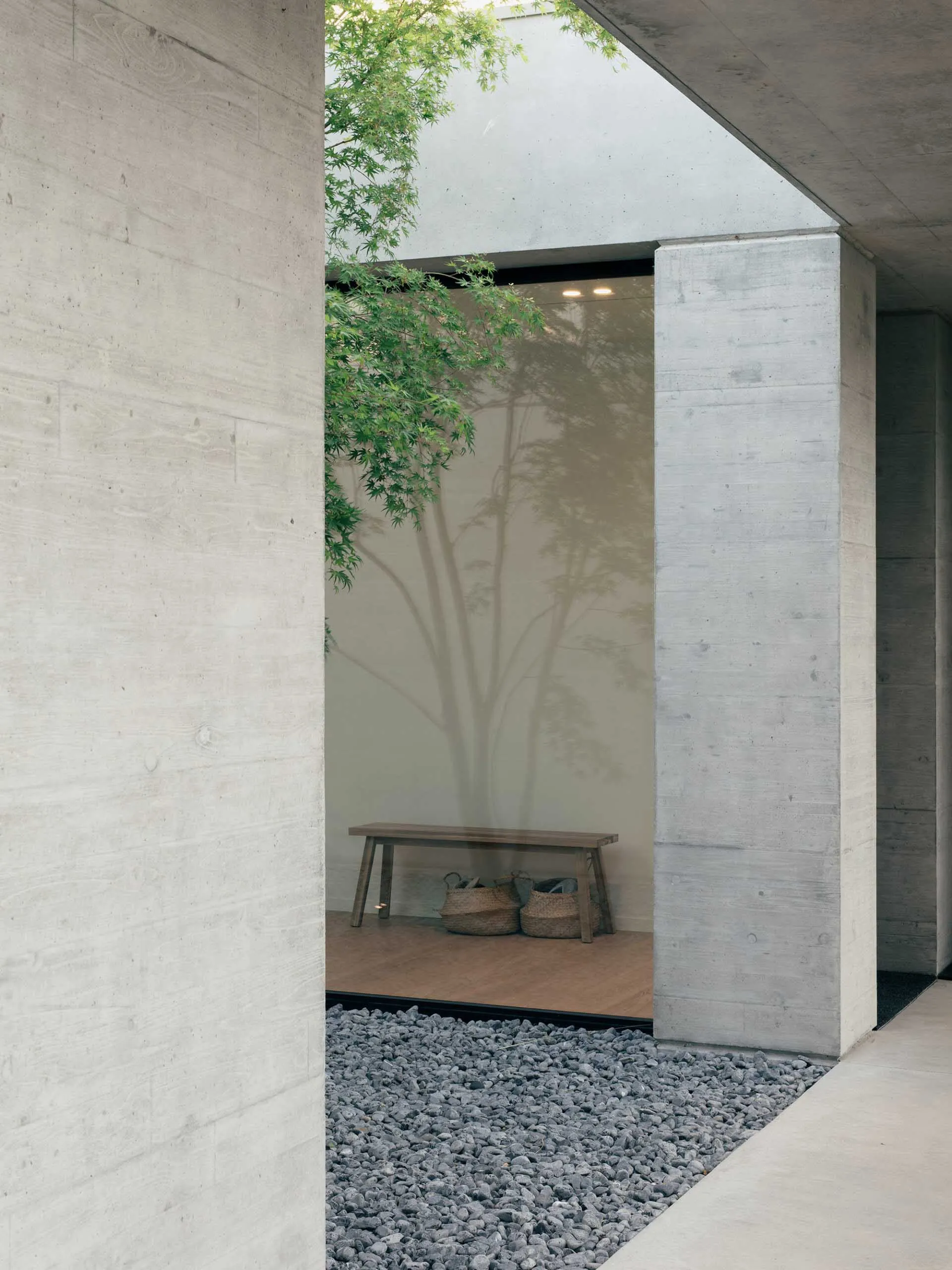 A minimalistic entryway with concrete walls and a wooden bench.