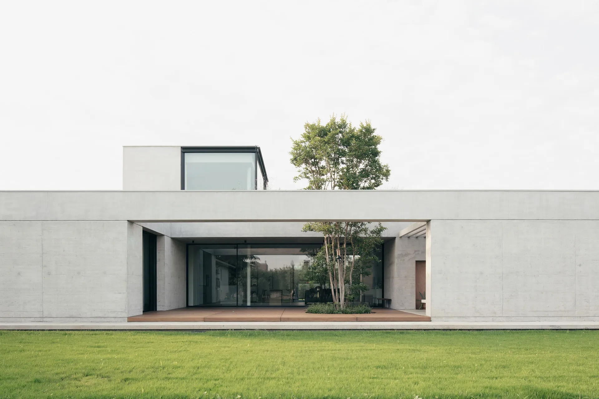 Modern house exterior featuring cement walls and a glass window.