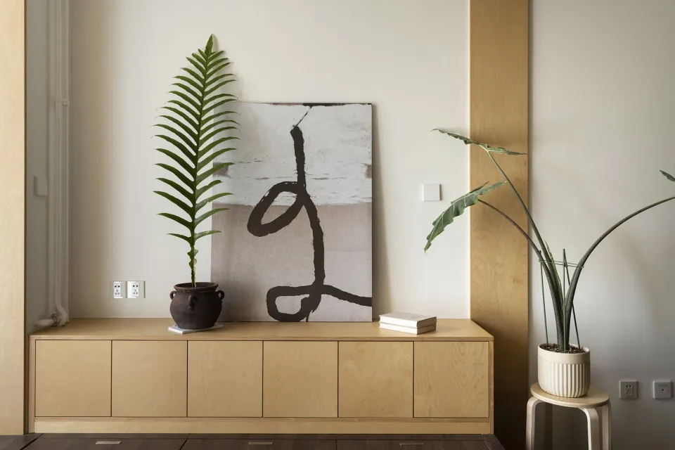 A modern interior design featuring a wooden cabinet adorned with tropical plants.