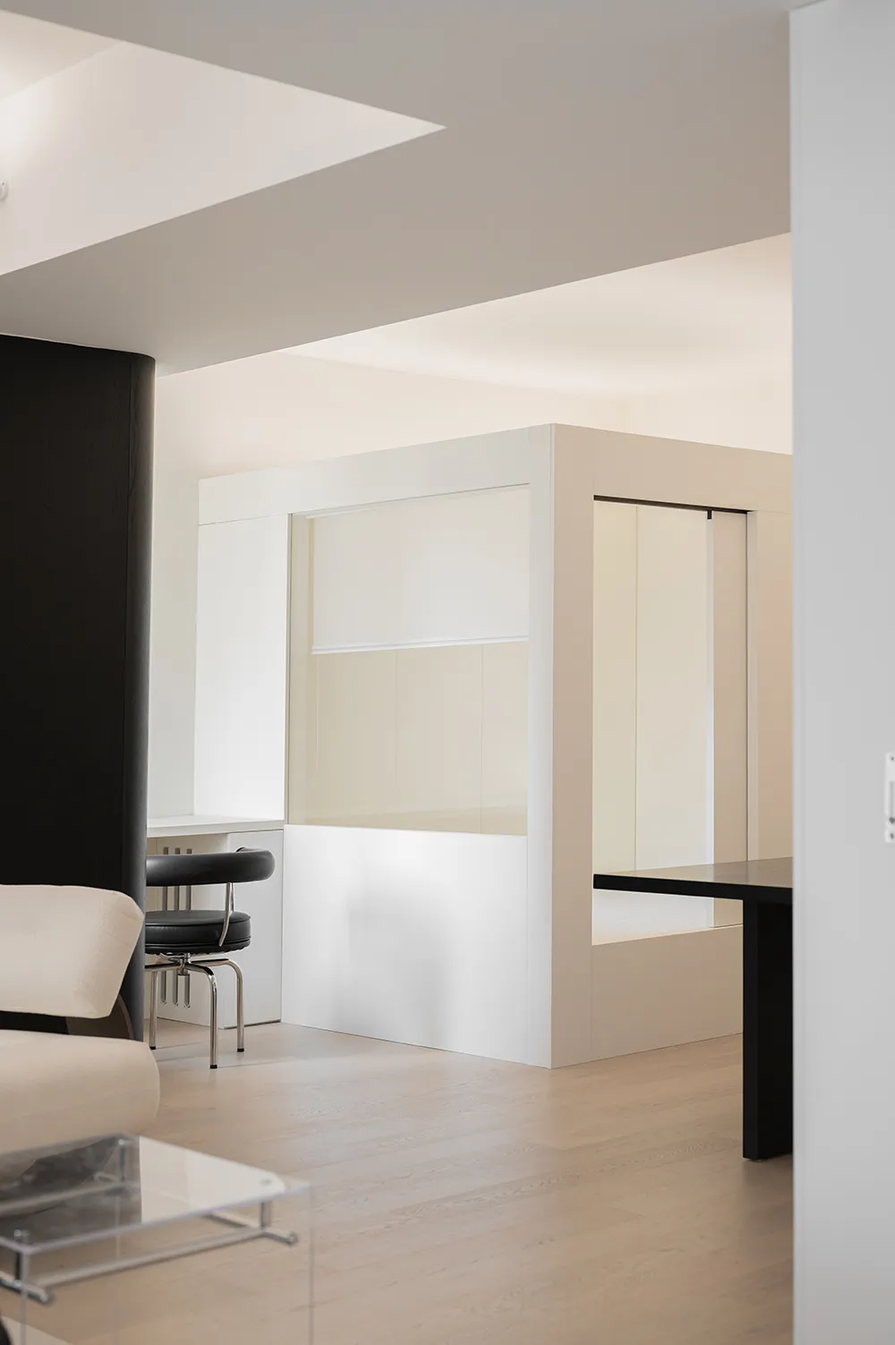 A modern, minimalist office space featuring glass walls, wooden surfaces, and metallic accents.