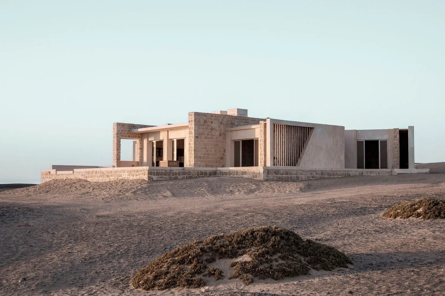 Modern residential building with minimalist design featuring stone and concrete materials.