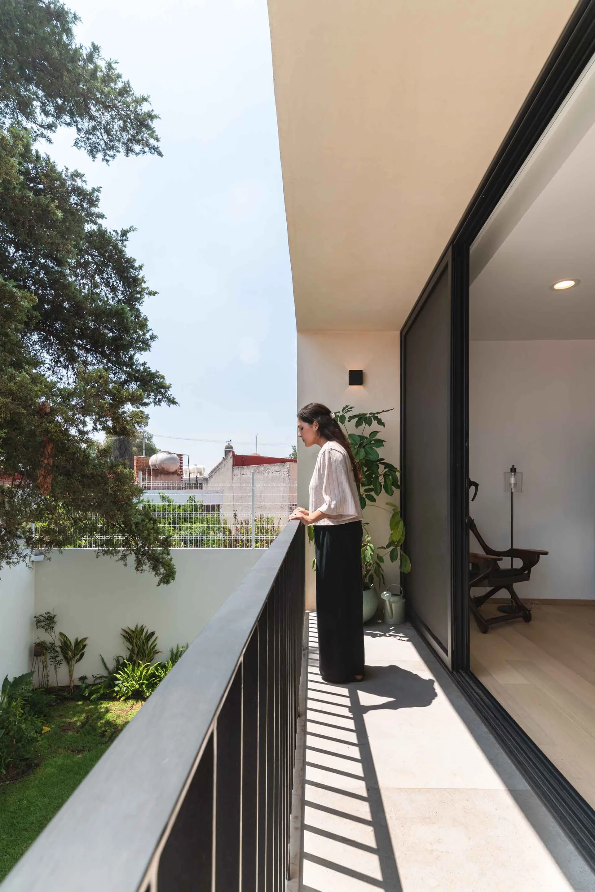 A woman standing on a modern residential balcony with concrete and glass elements.