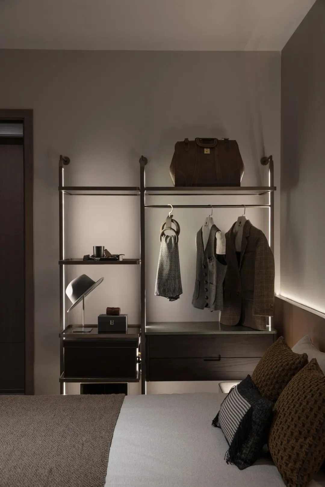 Modern bedroom featuring a metal storage unit with clothing, hats, and other items arranged neatly.