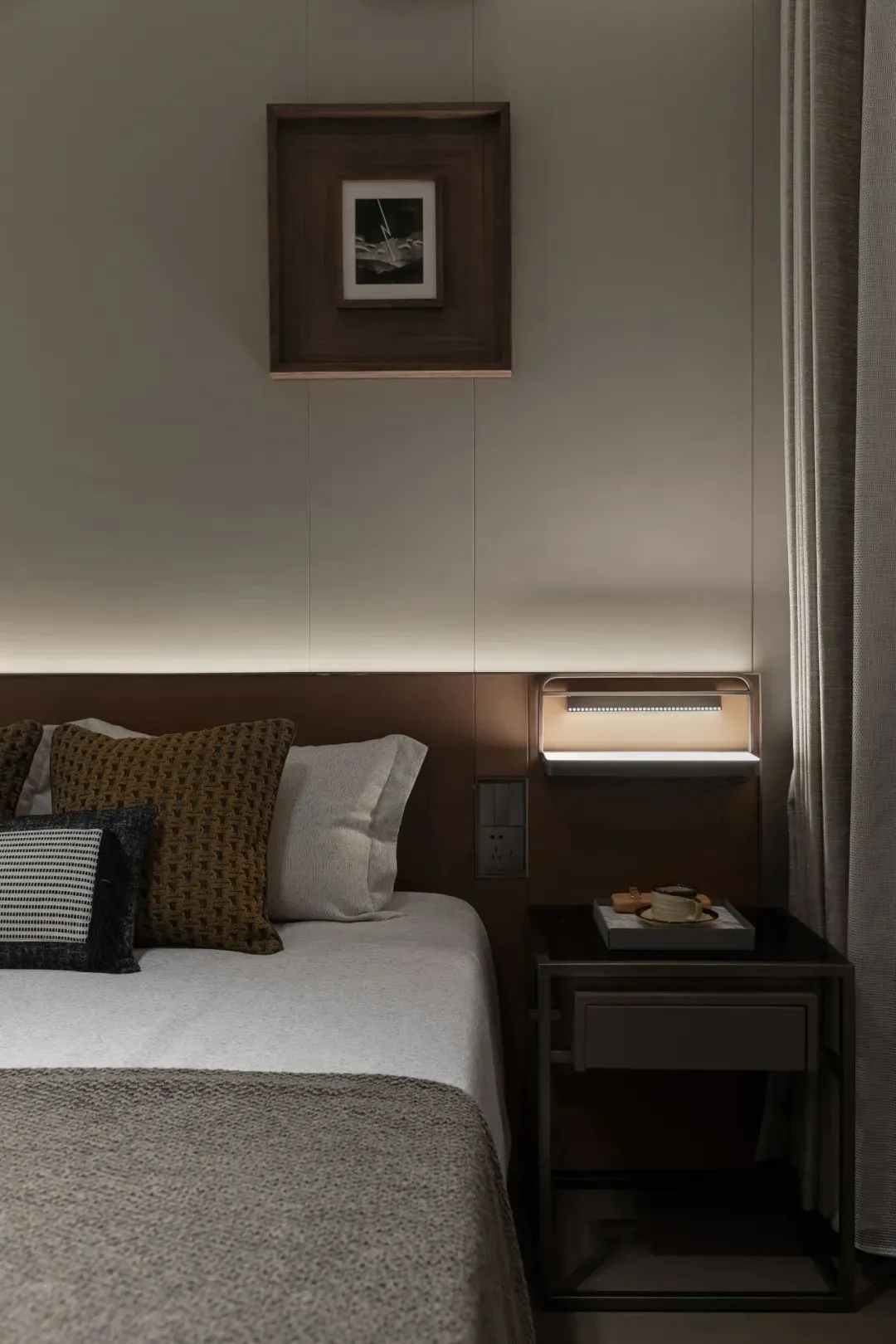 A minimalist bedroom with a bed, nightstand, and wall lights.
