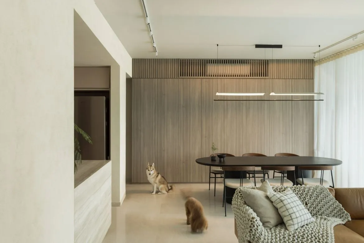 A modern residential interior with a wooden table, concrete floor, and metal chairs.
