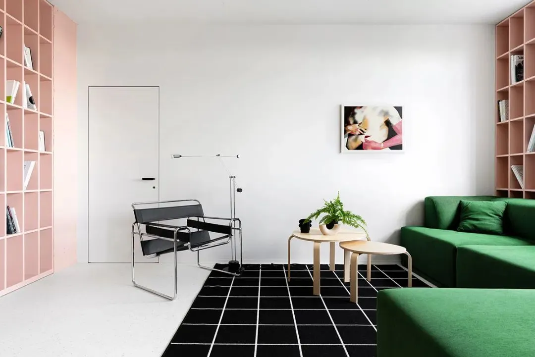Modern living room with a green fabric sofa, black and white grid carpet, and a minimalist design aesthetic