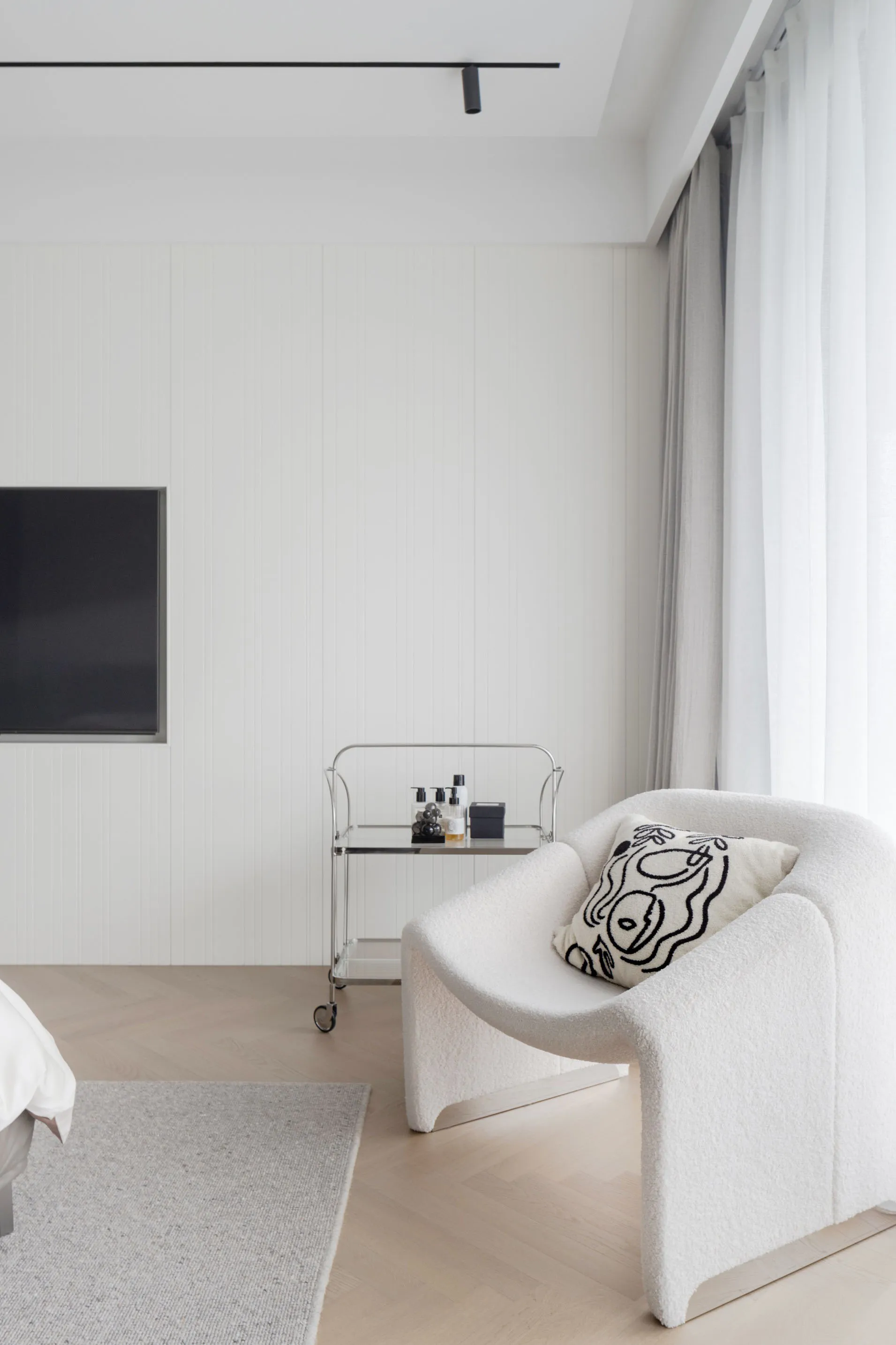 Modern minimalist bedroom with a textured fabric armchair.
