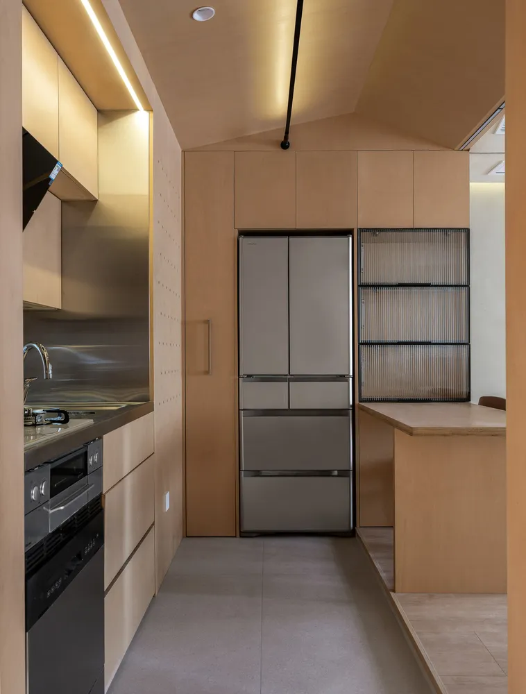Modern residential kitchen featuring minimalist design with wood finishes and sleek stainless steel appliances.