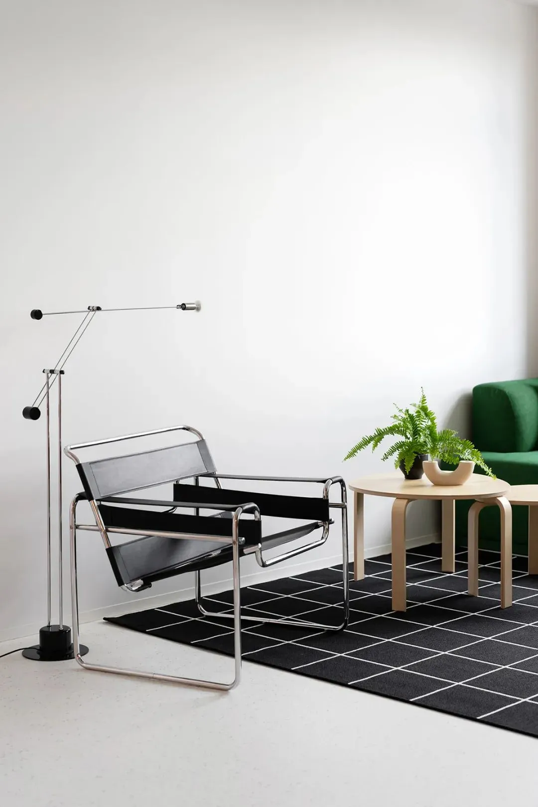 A modern living room featuring a black leather armchair, a round wooden coffee table with a green plant, and a black and whit