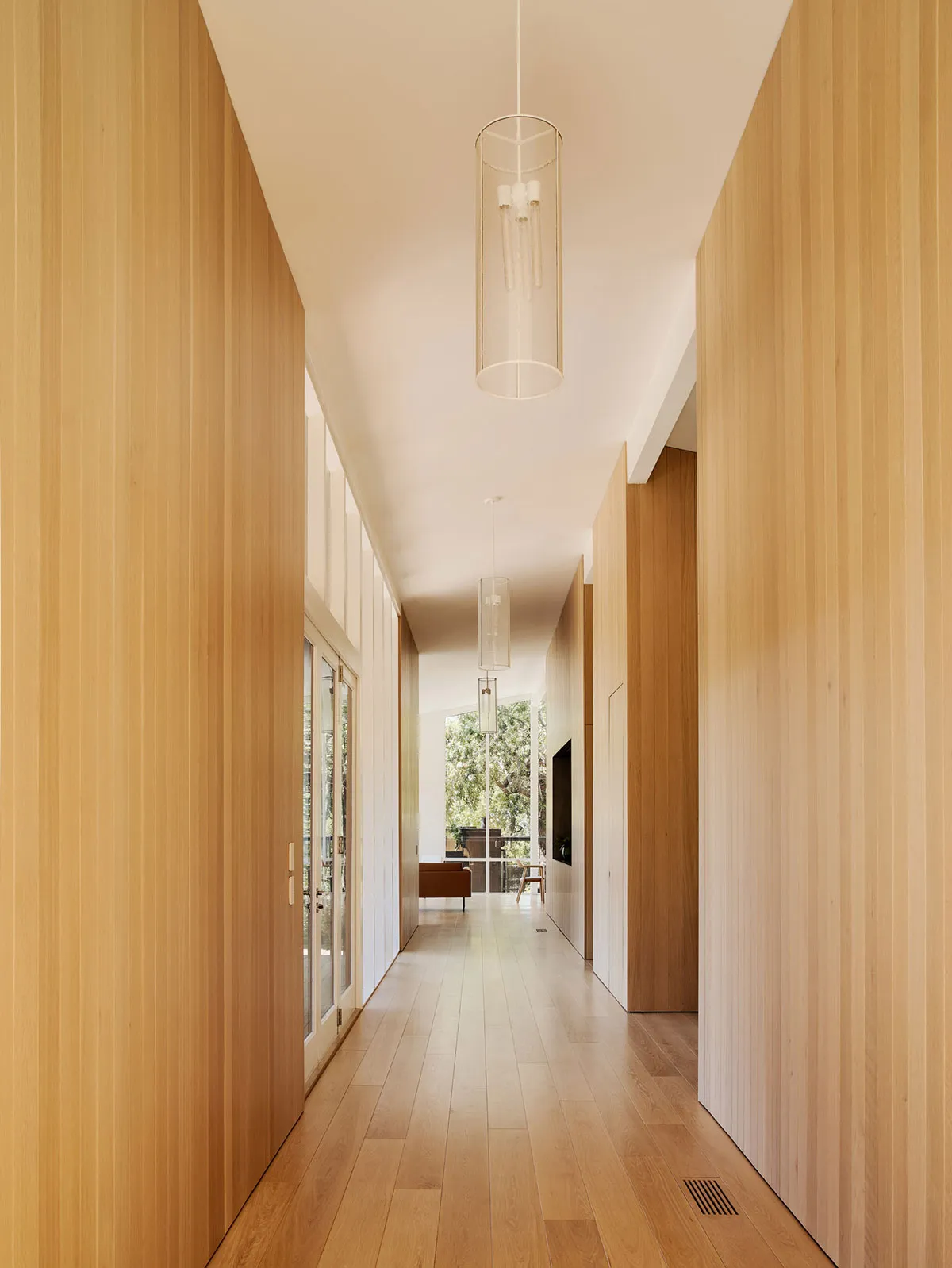 A modern corridor with wooden walls and floor, featuring minimalist design.