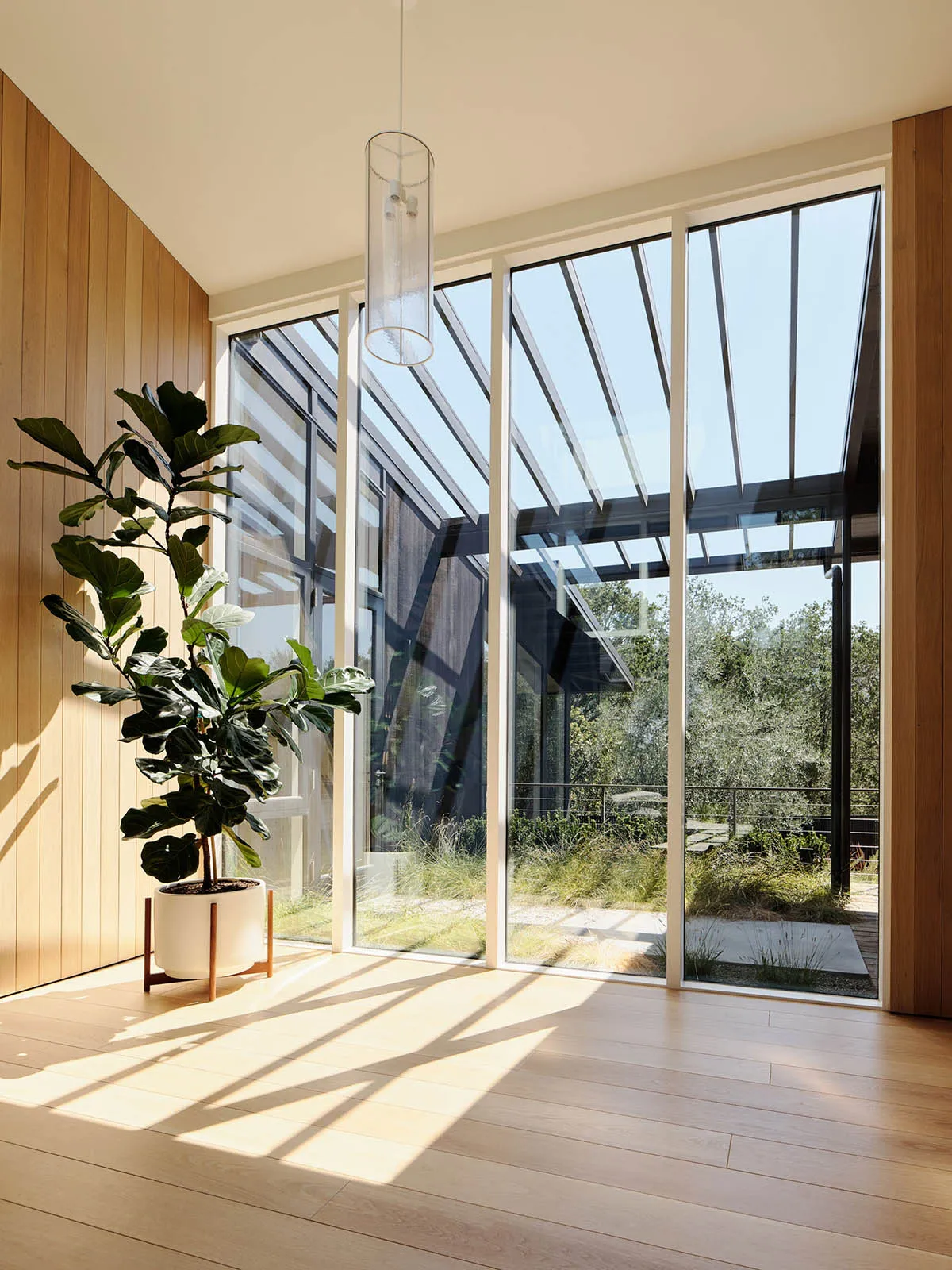 A modern living room featuring large glass windows and wooden flooring.