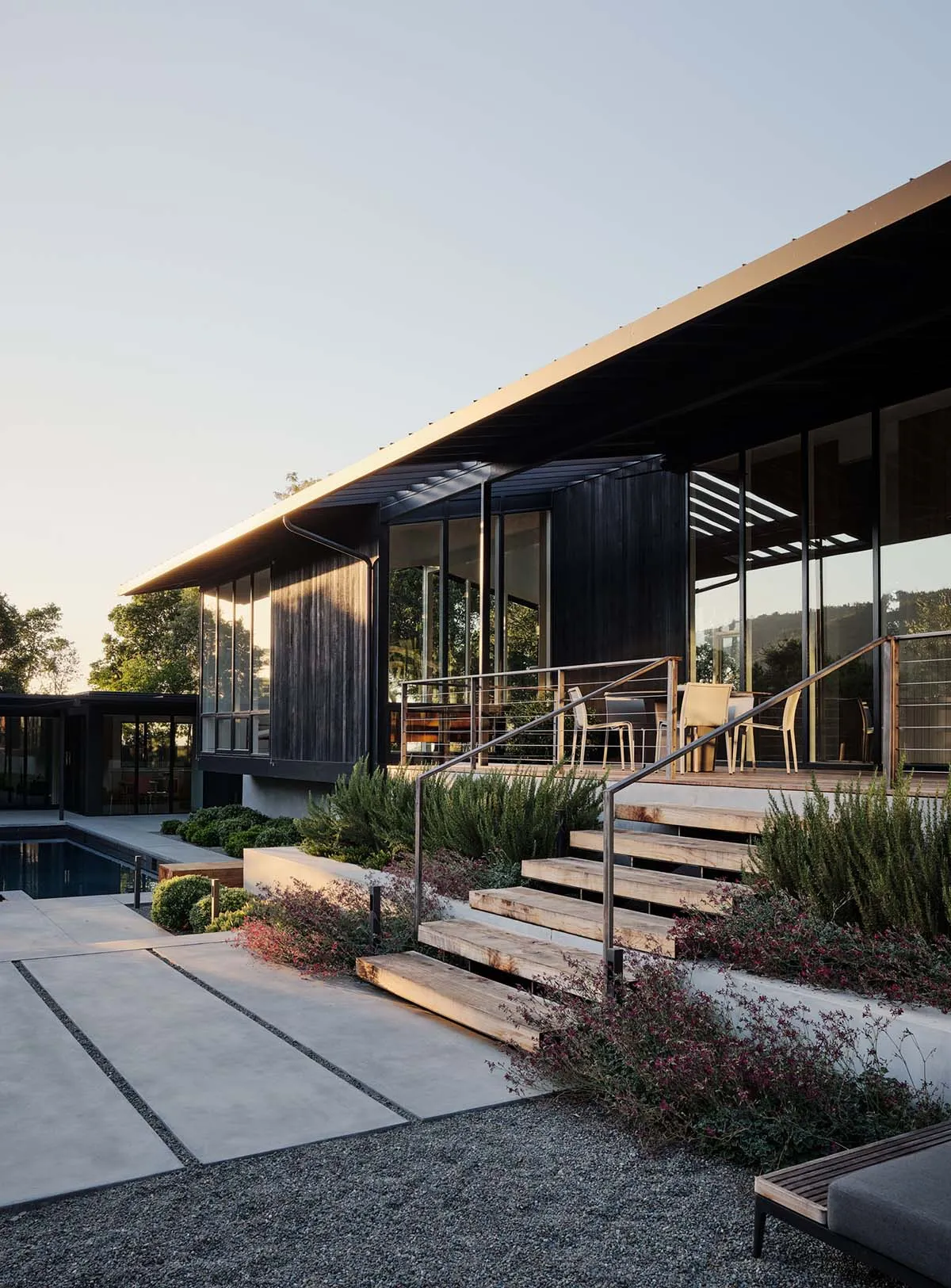 Modern residential exterior featuring wood, glass, and concrete materials with a terrace.