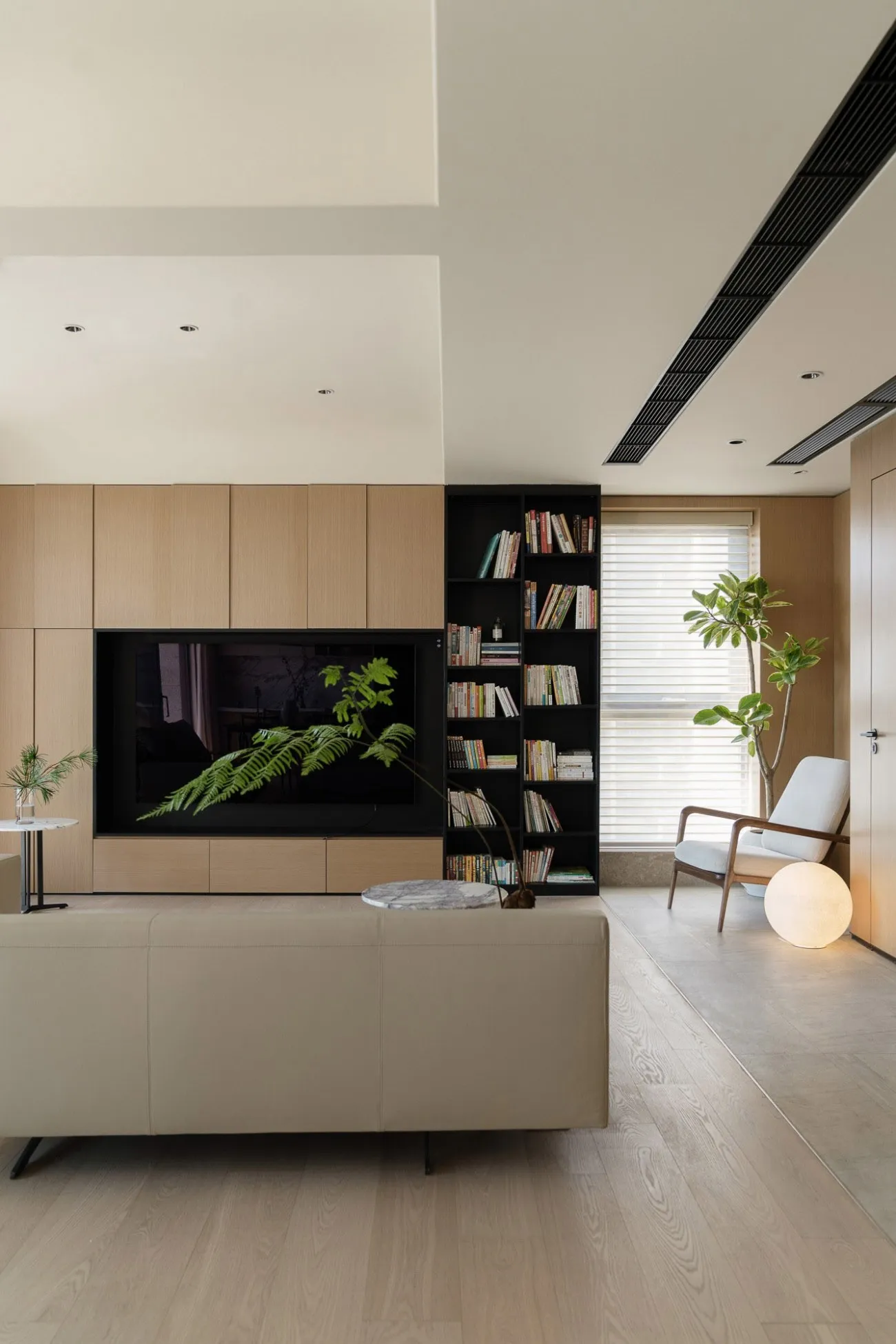 Modern living room with a wooden wall unit, a marble coffee table, and a large window with blinds. There is also a black book