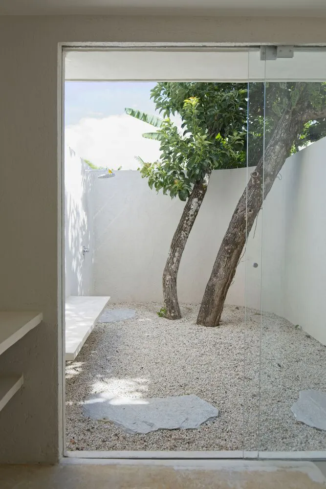 Modern residential garden featuring concrete fixtures and gravel path, with two trees providing shade.