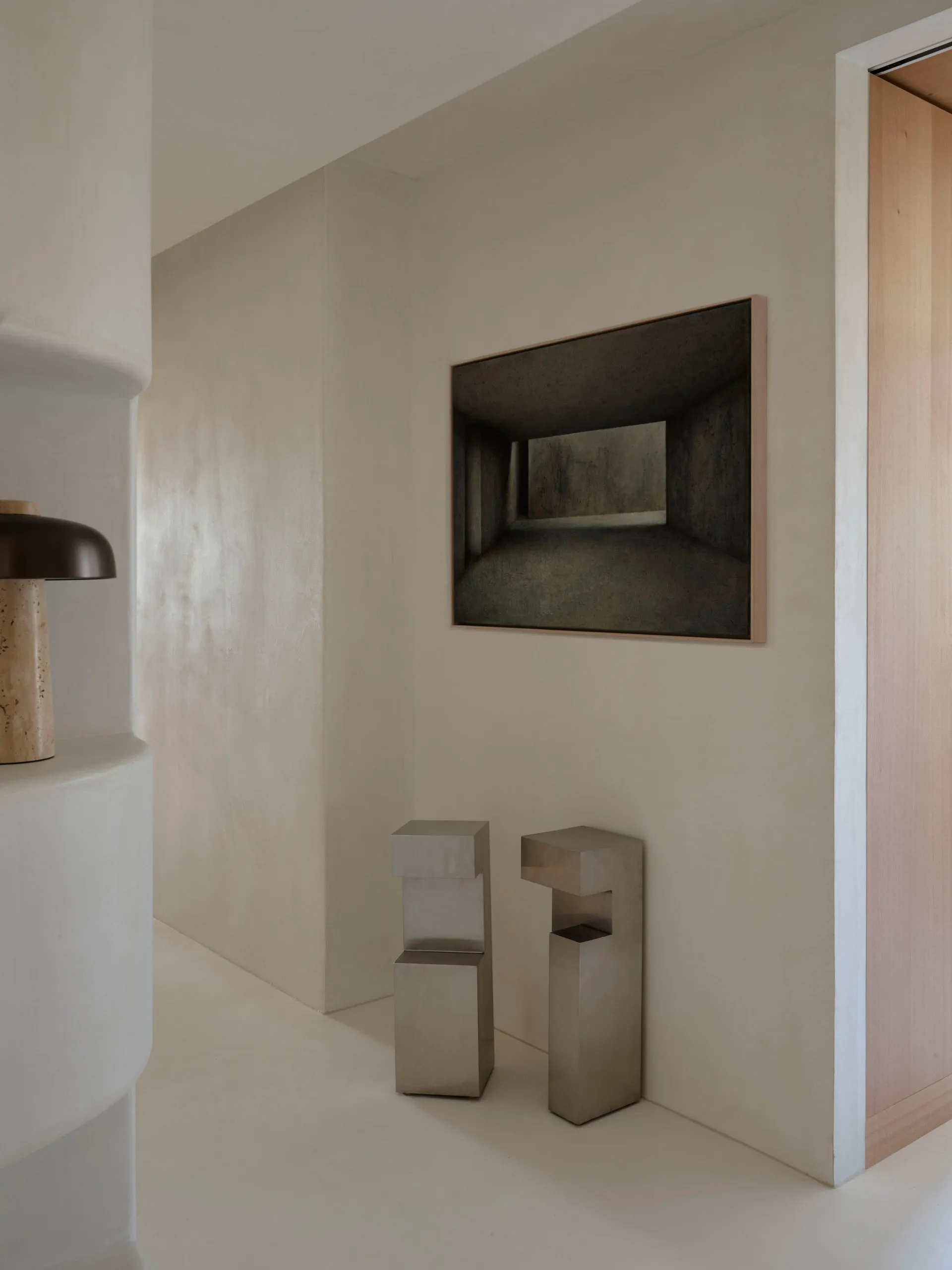 An entryway featuring metallic stools and concrete walls, creating a modern and minimalist atmosphere.