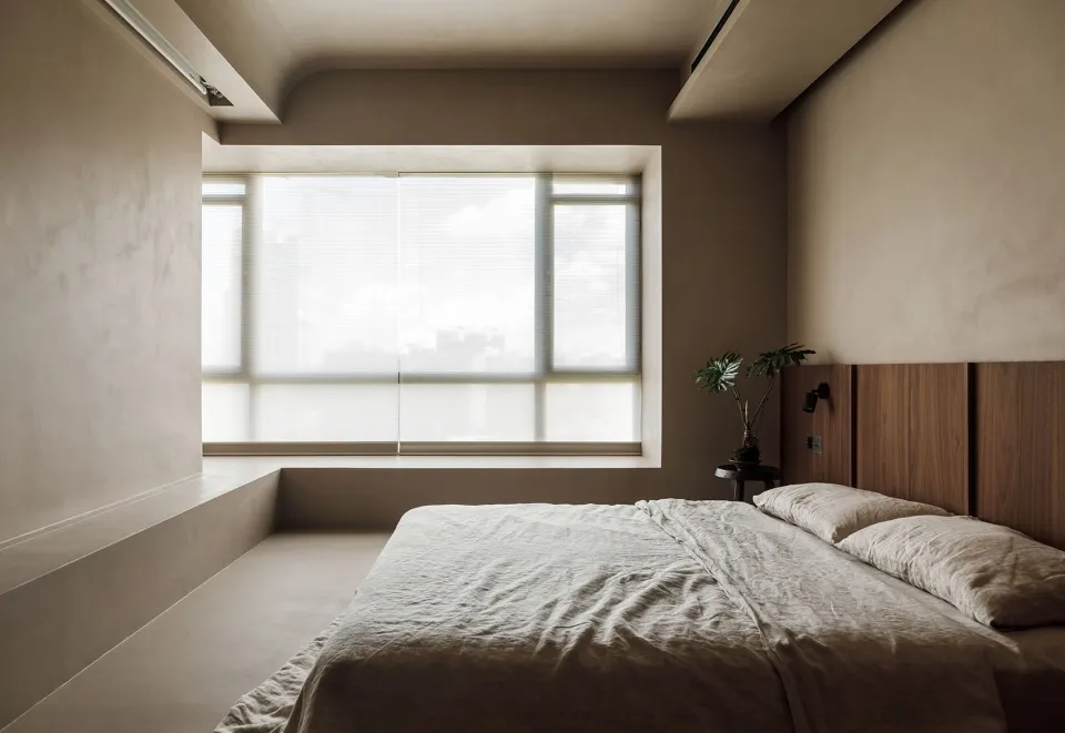 A minimalist bedroom with a concrete floor, bed, and large window.