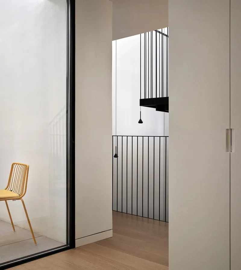 Modern minimalist room with white walls, wood floor, and yellow chair.