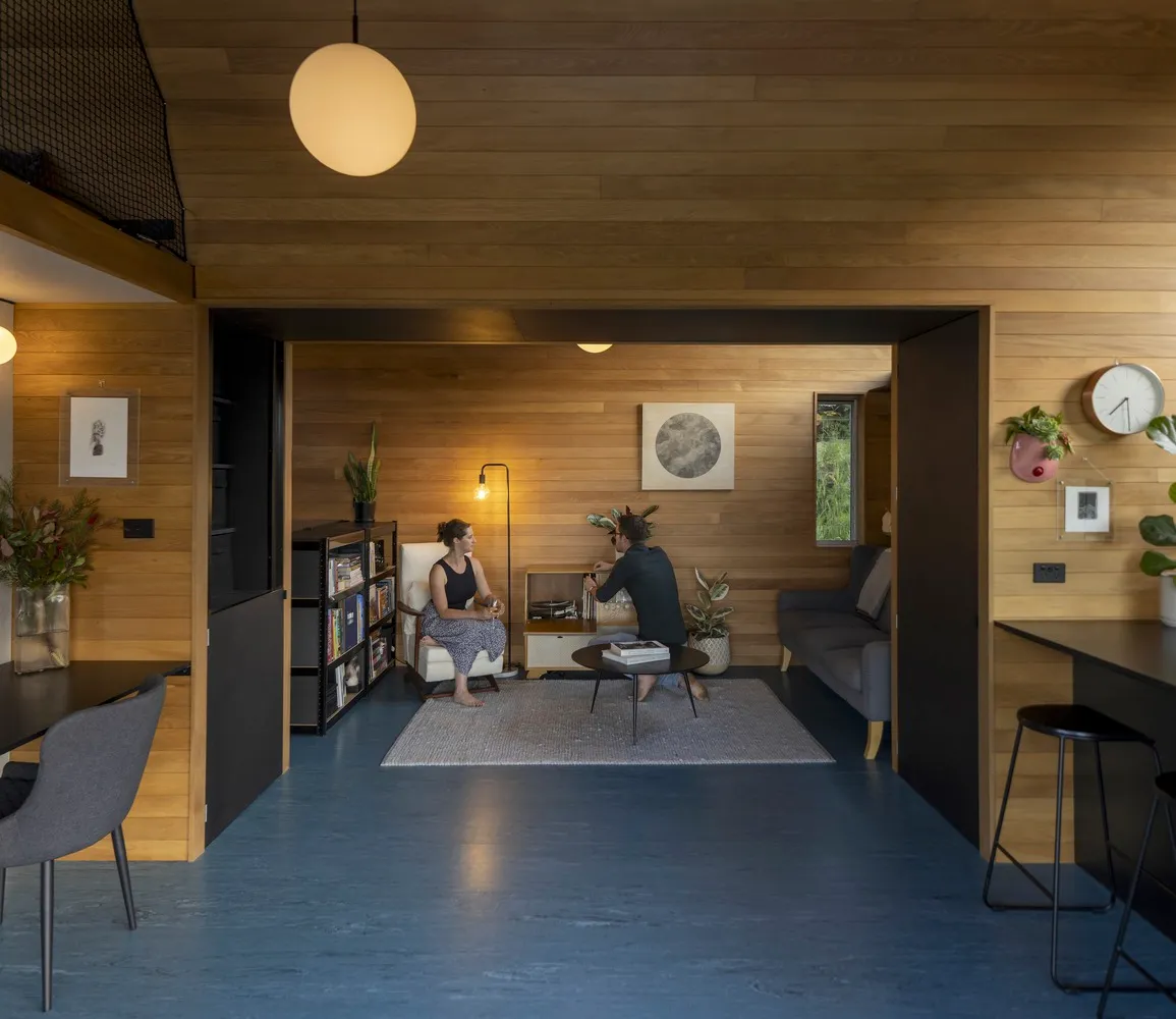 A modern living room featuring wood flooring and wood-paneled walls.