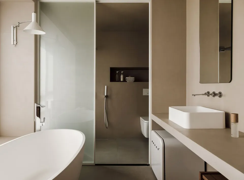Minimalist bathroom with a white bathtub, concrete walls, and a floating vanity with a white sink.