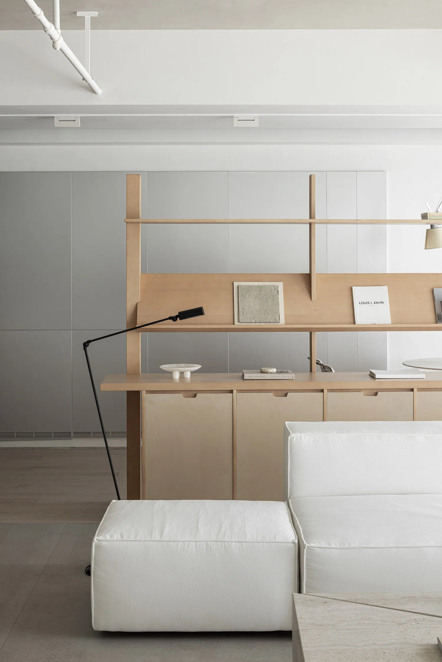 A minimalist living room featuring modern furniture, white leather and marble surfaces, and wood shelves.