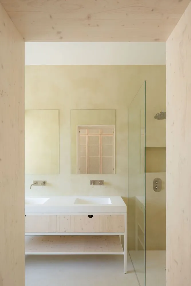 A minimalist bathroom with wood accents and a glass shower enclosure.