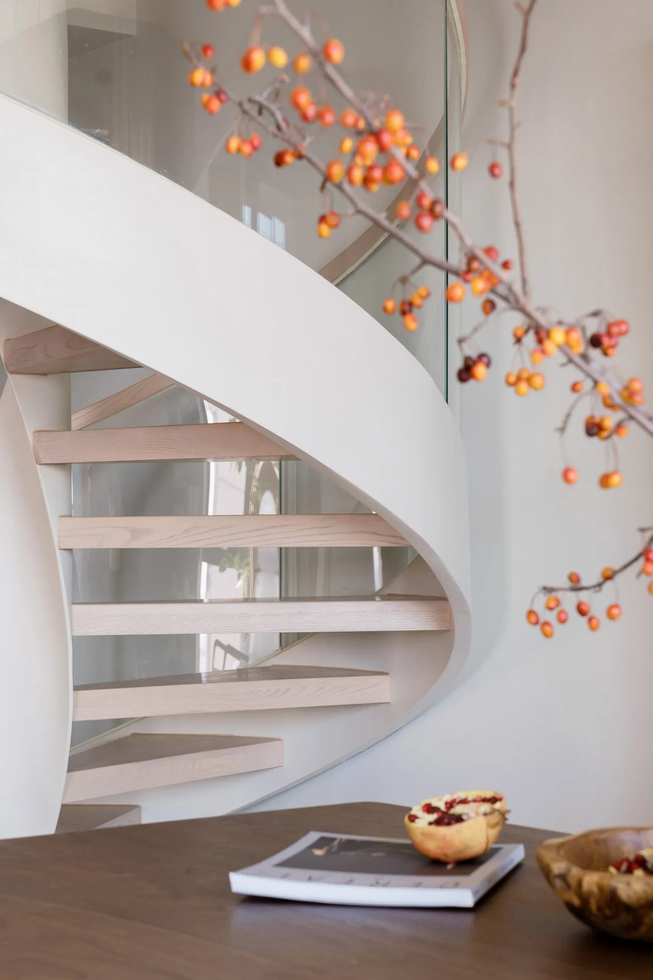 A modern white staircase with wooden steps and glass railings.