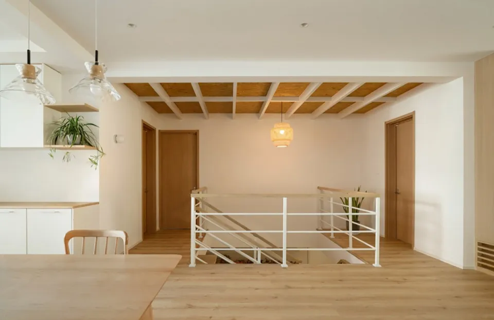 A minimalist interior design featuring a wooden ceiling with exposed beams and a modern dining area.