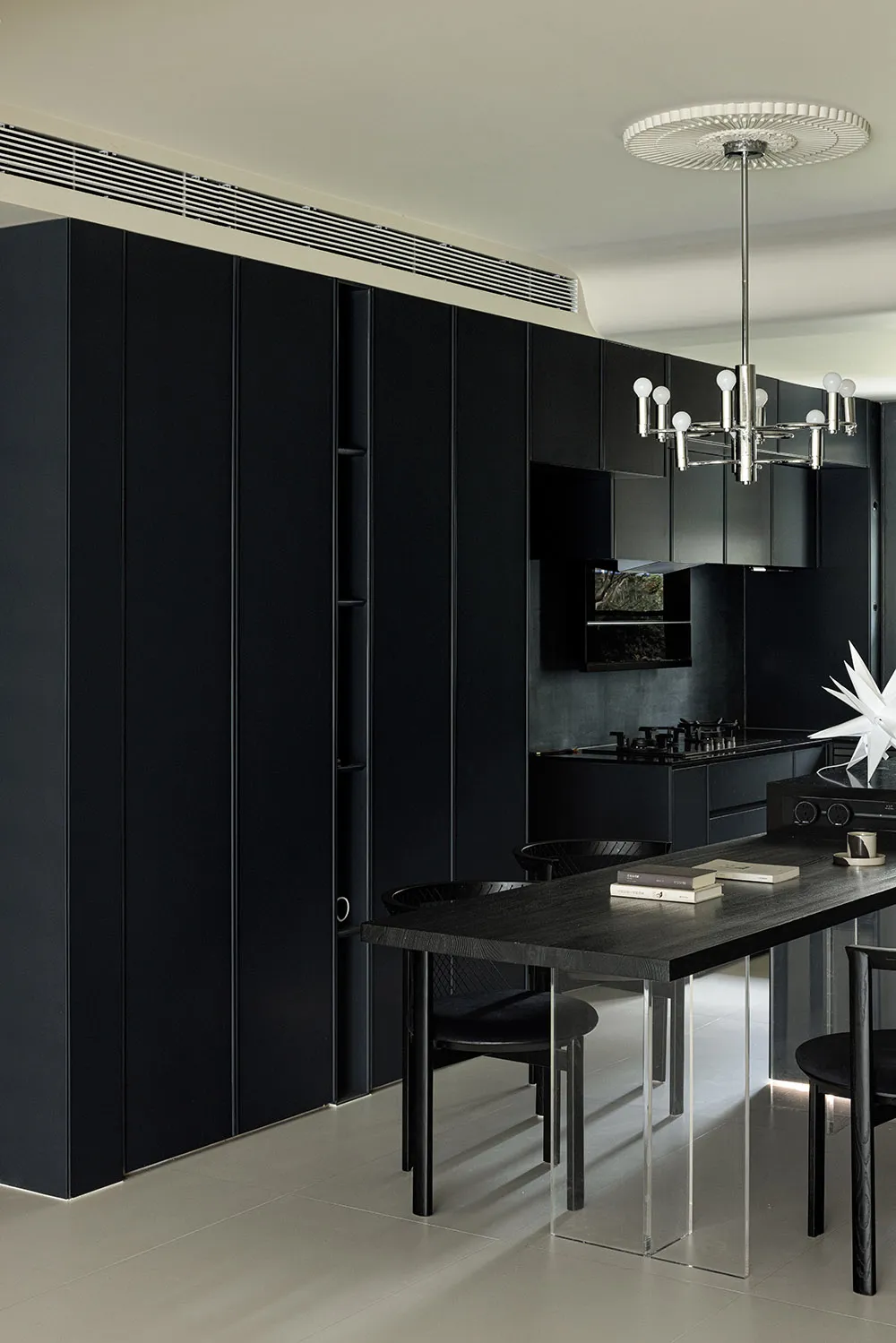 A modern kitchen with black cabinets and a long table.