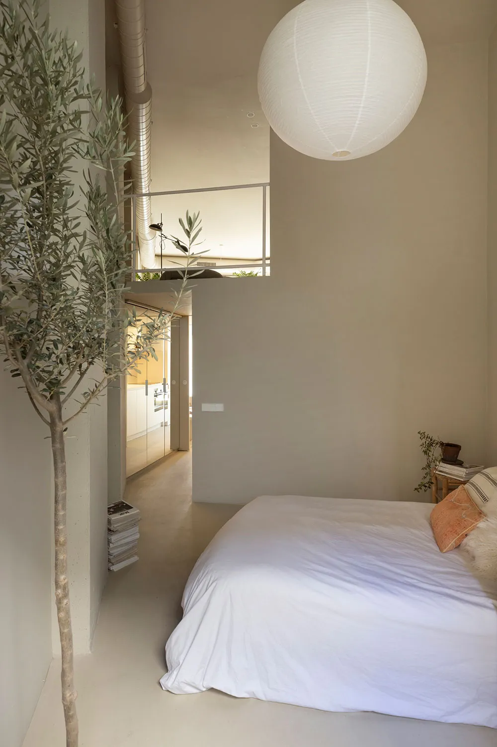 A minimalist bedroom with a concrete floor, a metal bed frame, and white textiles.