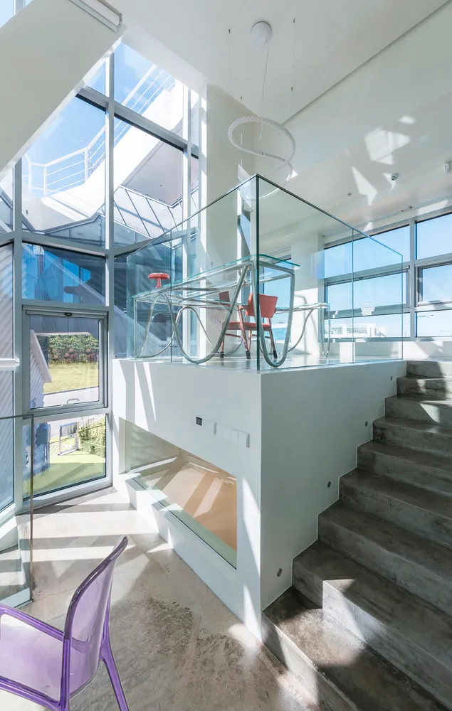 Glass and concrete modern interior design with staircase and seating area.